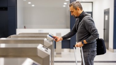 IAE blog image of a man scanning a code using his phone at an automated airport gate